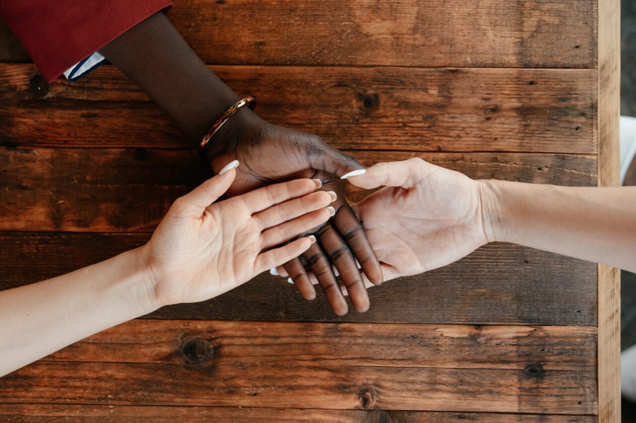 A stock image of diverse women stacking hands on a wooden table